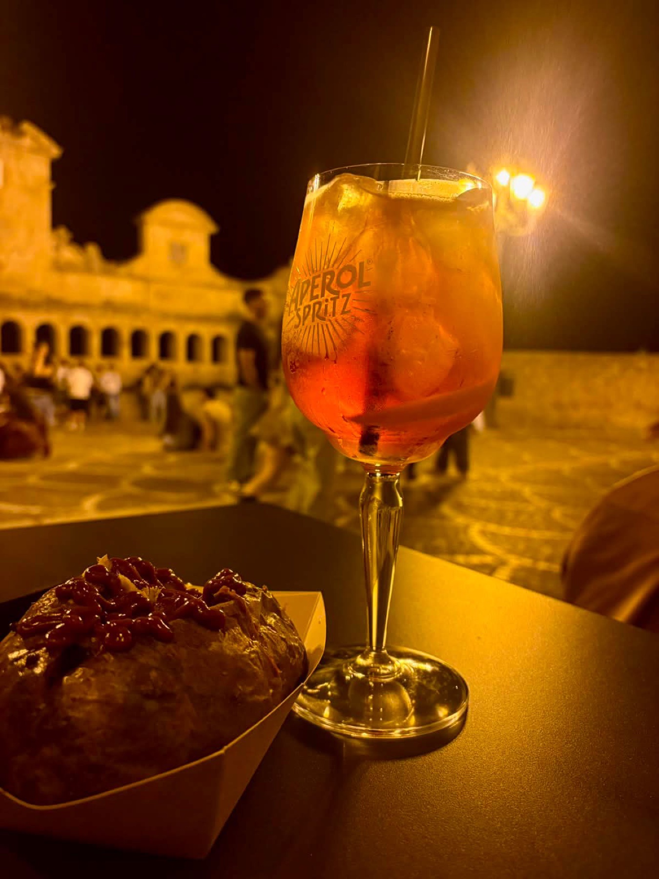 Cocktail al tavolo MÜD con la Granfonte illuminata sullo sfondo